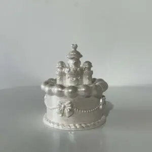 Castel ceramic decorativ argintiu pe masă albă.