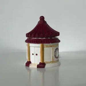 Figurină pavilion roșu cu stâlpi aurii pe alb.